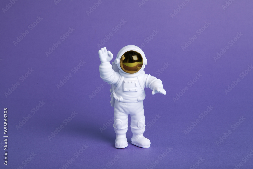 Wall mural an astronaut figurine in a spacesuit exploring a plain purple background
