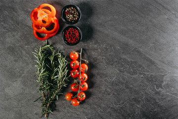 An aesthetic arrangement of sprigs of fragrant rosemary, three rings of red pepper, a branch of...
