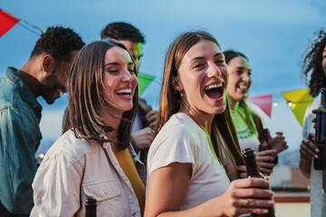 Two excited young adult women dancing together and having fun with friends at music festival....