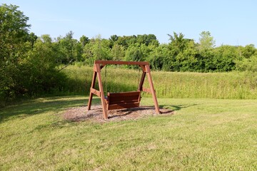 Fototapeta na wymiar The old wood swinging park bench in the park.