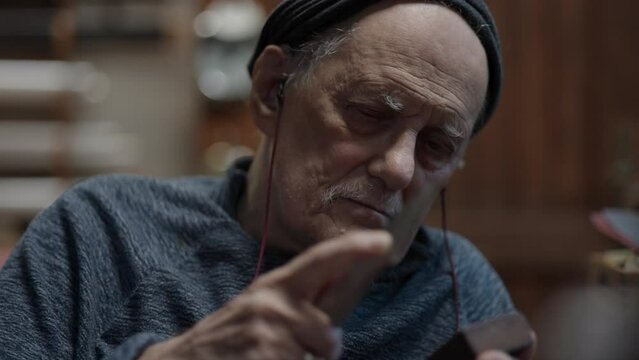 Senior gray haired male master in a wheelchair working at his workshop sharpening japanese deba knife