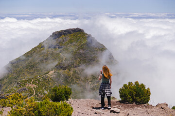 Travelling and exploring Madeira island landscapes and famous places. Young female tourist enjoying spectacular Pico Ruivo outdoor view. Summer tourism by Atlantic ocean and mountains.