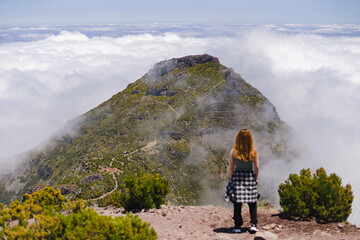 Travelling and exploring Madeira island landscapes and famous places. Young female tourist enjoying spectacular Pico Ruivo outdoor view. Summer tourism by Atlantic ocean and mountains.