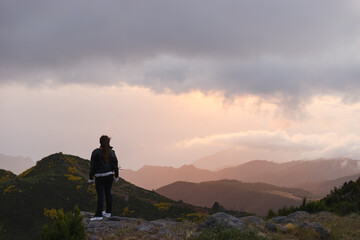 Travelling and exploring Madeira island landscapes and travel destinations. Young female tourist enjoying the sunrise and outdoor spectacular scenery. Summer tourism by Atlantic ocean and mountains.