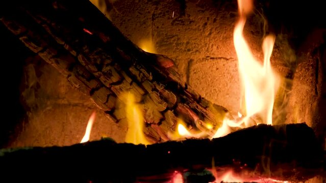 Burning firewood in fire-box of fireplace in country cottage. Rustic cooking oven with burning logs.