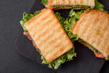 Delicious crispy sandwich with toast, salmon, avocado, tomatoes, salt, spices and herbs