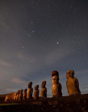 Moai stand at night illuminated beneath a sky full of stars on Easter Island at Tongariki site, Chile; Easter Island, Isla de Pascua, Chile