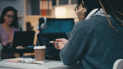 Computer system analysts discussing new project, checking software on laptop