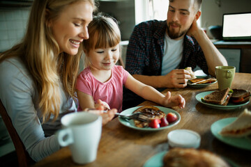 Young family having breakfast together in the morning in the kitchen at home