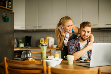 Young woman embracing her partner after coming back from a workout in the kitchen at home