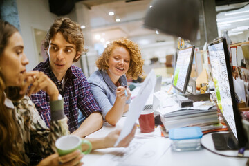 Young group of coworkers going over paperwork in the office of a startup company
