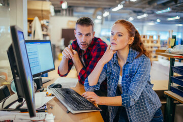 Young man and woman using a computer while working in a printing press office
