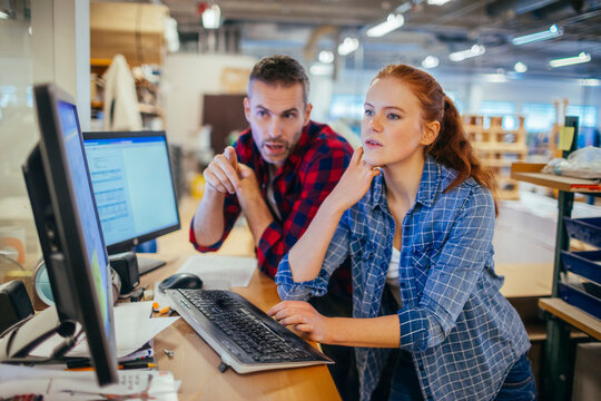 Young man and woman using a computer while working in a printing press office