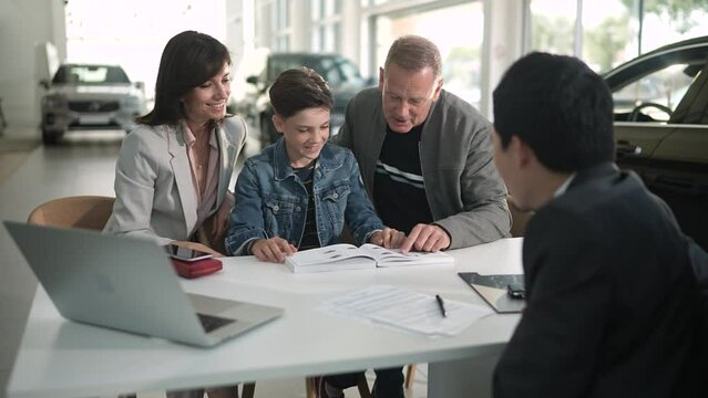 Young family closing the deal with a salesmen on their new car at the dealership