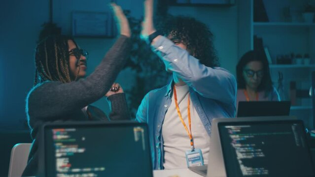 Multiethnic IT developers happy with finished project, high fiving each other