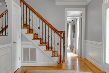 Interior of Modern Luxury Foyer with Wood Stairs and Metal Support Rod with Arch Mirror and Trim...