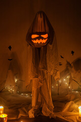 Scary ghost holding Jack o lantern in dark. Scary atmospheric halloween decorations and person...