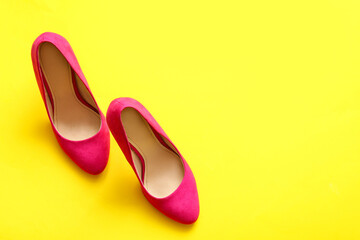 Pair of stylish high heeled shoes on yellow background