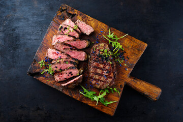 Barbecue dry aged angus roast beef steak with rocket lettuce and herbs served as top view on a...