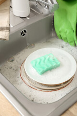 Plates with cleaning sponge in sink, closeup