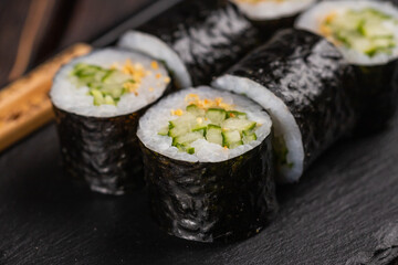 Maki sushi roll with cucumber and sesame with chopsticks close-up. Sushi menu. Japanese food.