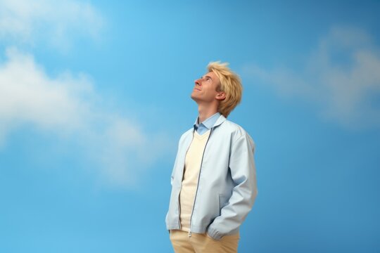 A man standing in front of a clear blue sky. This image can be used to represent freedom, success, or a positive outlook on life.