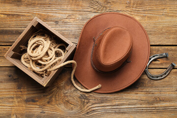 Cowboy hat, lasso and horseshoe on wooden background