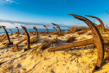 Rusty old anchors on the beach at the Anchor Cemetary graveyard at Praia do Barril beach, in...