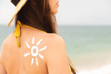 happy girl with the sun on her back by the sea in nature. drawing with cream in the shape of a sun...