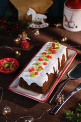 Dessert, Polish poppy seed cake with apples and candied fruits, covered with sugar icing, in Christmas style on a brown concrete background. Merry Christmas. Polish cuisine