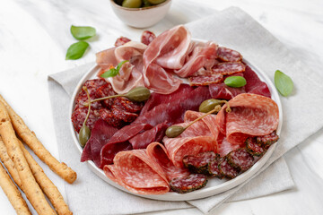 Food aperitif Italian prosciutto ham, parma ham, salami, bresaola beef olives and grissini breadstick. Charcuterie plate
