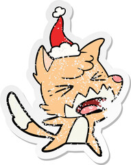 angry hand drawn distressed sticker cartoon of a fox wearing santa hat