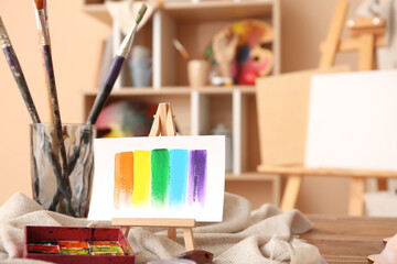 Glass with brushes, paints and mini easel in artist's studio