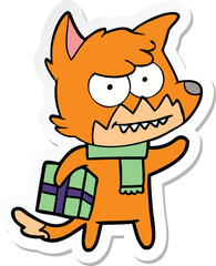 sticker of a cartoon grinning fox with christmas present