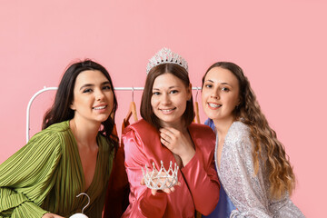 Young women with tiaras for prom on pink background