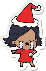 hand drawn sticker cartoon of a girl crying and pointing wearing santa hat