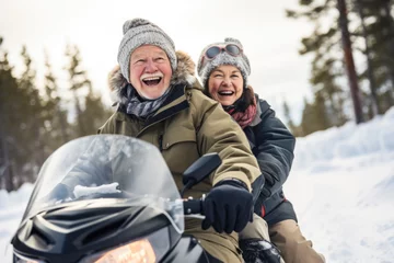 Fotobehang Happy active senior couple in winter doing snowmobiling. © Maria