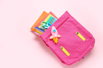 Backpack with rocket made of plasticine and stationery on pink background