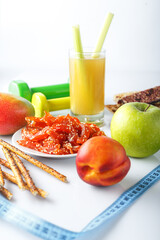 glass of celery juice, crackers and fruits, meat snacks on a plate, dried pieces of Carpaccio meat, dumbbell and sports ruler, on a white isolated background