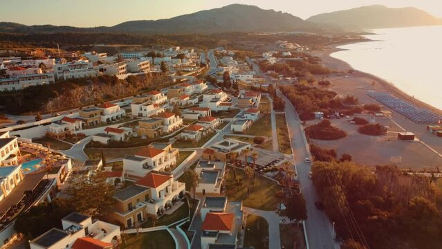4k Aerial view sunrise over kiotari beach in Rhodes, greece. Smooth cinematic footage. Classic Greek white buildings and blue waters.