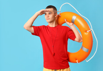 Male lifeguard with ring buoy on blue background - obrazy, fototapety, plakaty