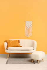 Cozy white sofa and ottoman near orange wall with wicker decor
