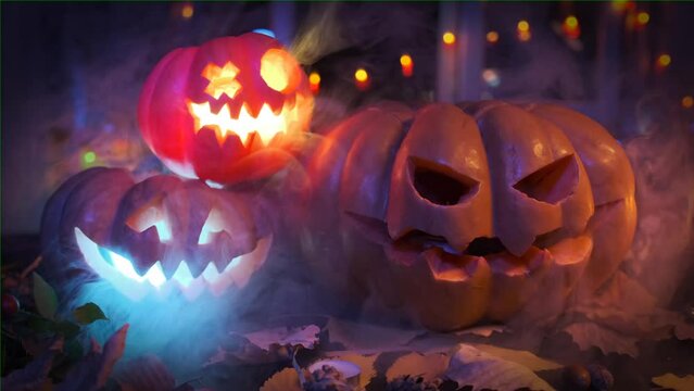 Three pumpkins glow with colorful lights, foggy festive Halloween invitation background. Beautiful creepy Jack-o'-lanterns in smoke.