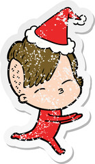 hand drawn distressed sticker cartoon of a girl in onesie wearing santa hat