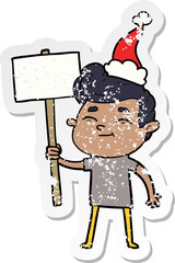 happy hand drawn distressed sticker cartoon of a man with sign wearing santa hat