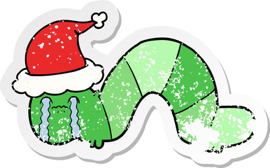 hand drawn distressed sticker cartoon of a caterpillar obsessing over his regrets wearing santa hat