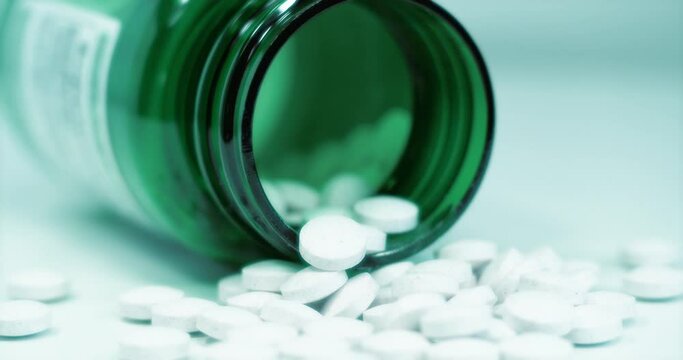 Overdose. White tablets and green container for nutritional supplements. Cinema 4K 60fps video with cinema effects