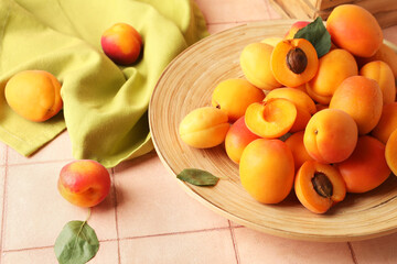 Plate with sweet apricots on pink tile table