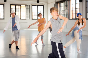 Teenager girl and boys exercising hip-hop dancing indoors