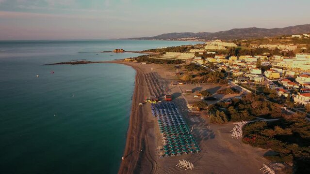 Aerial view sunrise over kiotari beach in Rhodes, greece. Smooth cinematic footage with buildings in the foreground 4k. Crystal clear waters. glassy.